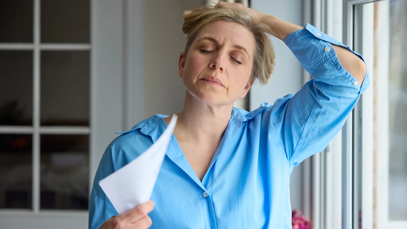 Woman experiencing a hot flash, a common menopause symptom evaluated in clinical research.