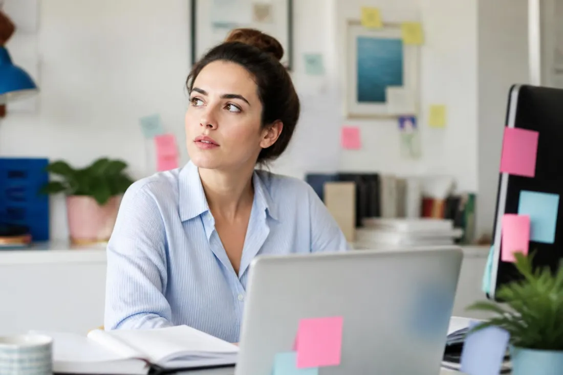 Adult overwhelmed at a busy desk Woman at a desk covered in sticky notes and open tabs, reflecting the focus and organization challenges addressed in ADHD clinical trials